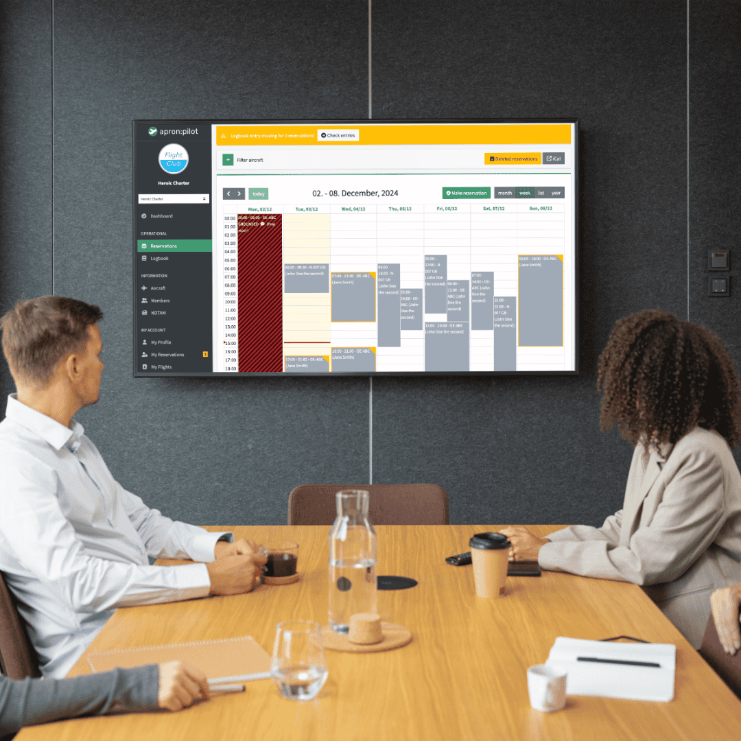 people sitting in front of a tv which is showing the calendar view of the application